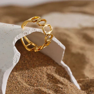 18K gold-plated open ring with geometric design displayed on sandy surface