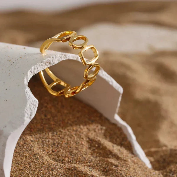 18K gold-plated open ring with geometric design displayed on sandy surface