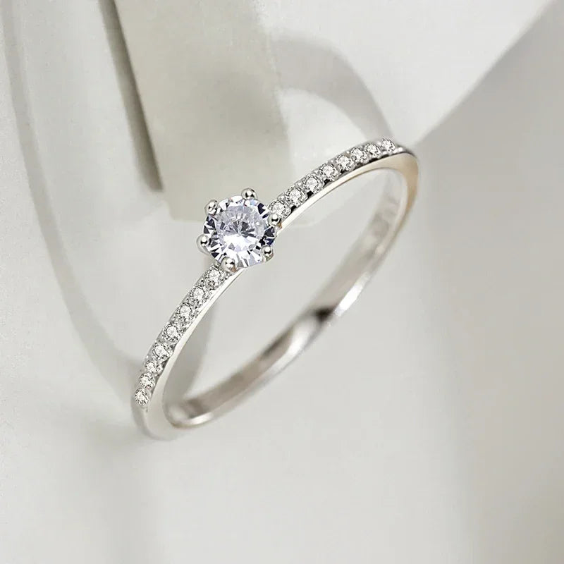 925 silver solitaire ring with round center stone and pavé band on white background