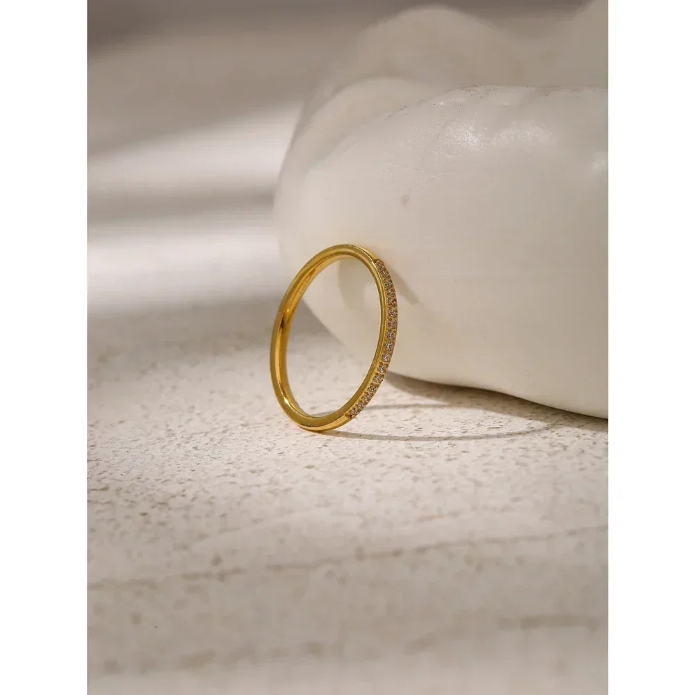 Elegant gold-plated ring with pavé set crystals on a textured stone surface