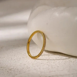 Elegant gold-plated ring with pavé set crystals on a textured stone surface