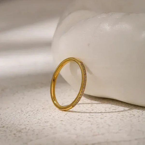 Elegant gold-plated ring with pavé set crystals on a textured stone surface