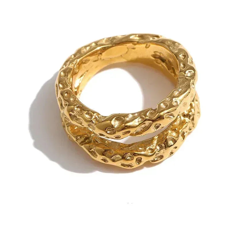 Textured gold-plated rings with a hammered finish, stacked on a white background.
