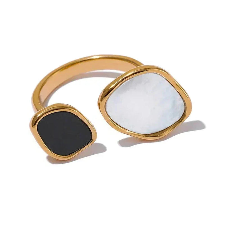 Two gold-rimmed rings with white and black stones on a white background