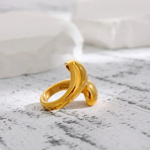 Elegant 18K gold-plated open ring with a modern sculptural twist design on a textured surface