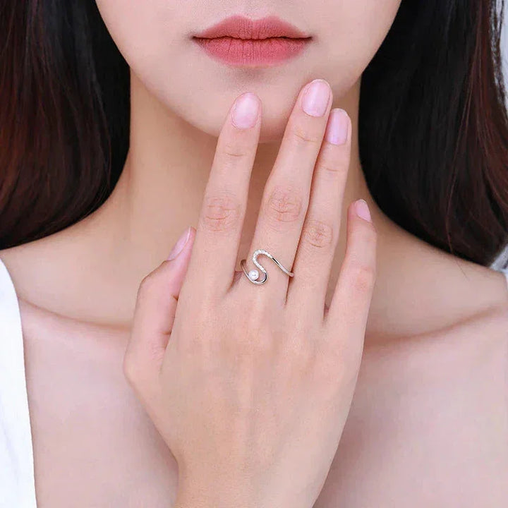 Woman wearing a silver S-shaped open ring with small crystal accents on her finger.