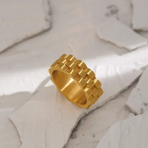 Gold-plated geometric band ring with scalloped edges on a neutral background