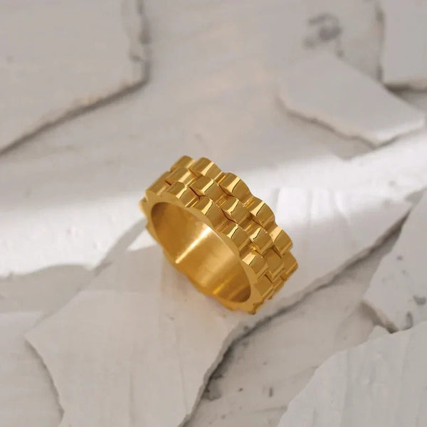 Gold-plated geometric band ring with scalloped edges on a neutral background
