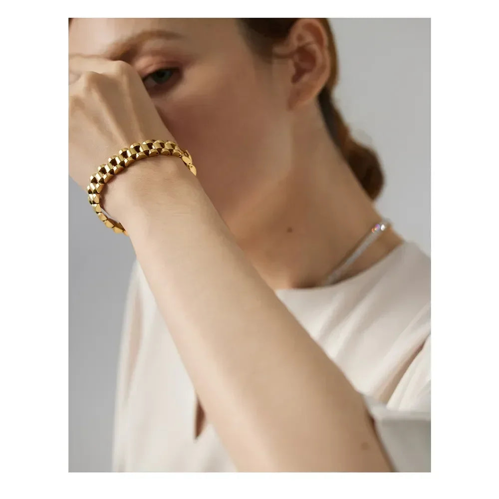 Woman wearing a chunky 18K gold-plated bracelet and silver necklace
