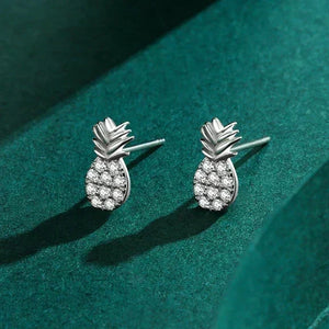 Silver pineapple-shaped earrings on a green textured surface