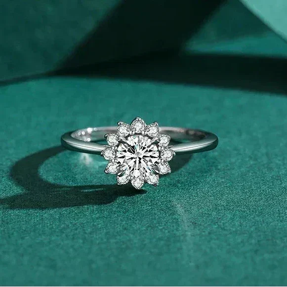 Silver ring with a diamond flower design on a teal fabric background