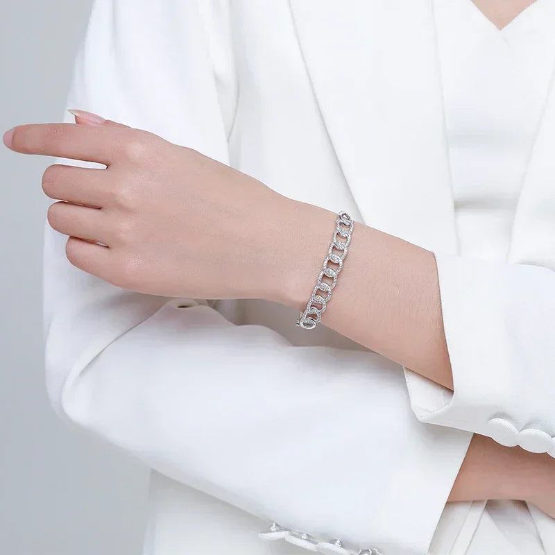 Woman wearing a silver chain link bracelet on her wrist, dressed in a white suit.