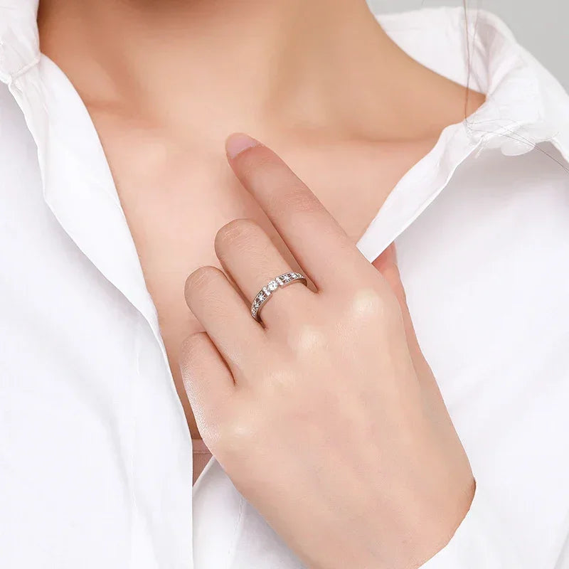 Woman wearing a 925 silver ring with clear stones, modeling jewelry on her hand in white shirt