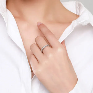 Woman wearing a 925 silver ring with clear stones, modeling jewelry on her hand in white shirt