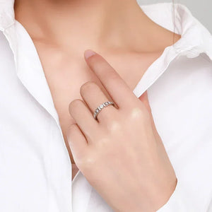 Woman wearing a 925 silver ring with clear gemstones on her finger, white blouse visible.