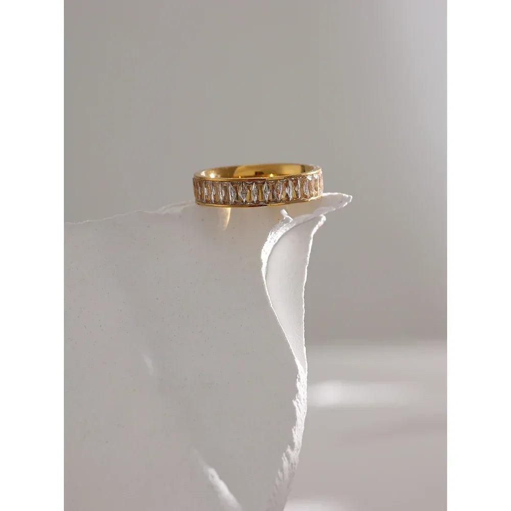 18K gold-plated ring with baguette-cut clear stones on a white textured surface