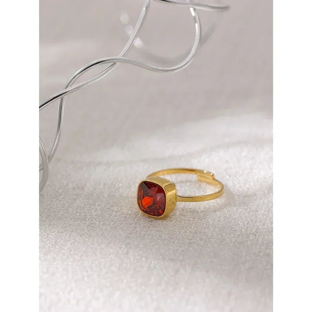18K gold-plated ring with square red gemstone on textured white surface