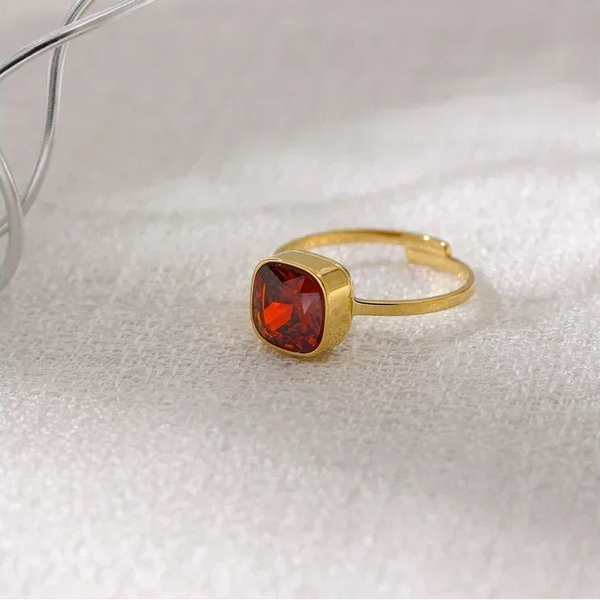 18K gold-plated ring with square red gemstone on textured white surface