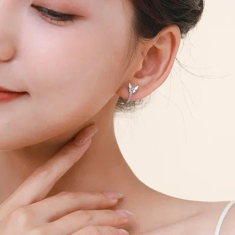 Woman wearing delicate butterfly-shaped 925 silver stud earring, close-up view