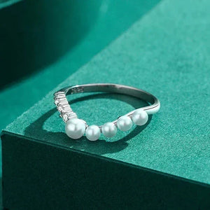 Silver ring with pearls on a green surface