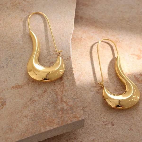 Pair of gold earrings on a beige marble surface