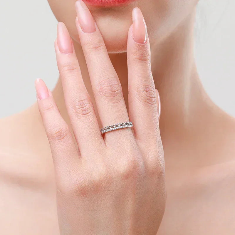 Woman wearing a silver band ring with sparkling stones on her finger, elegant manicure