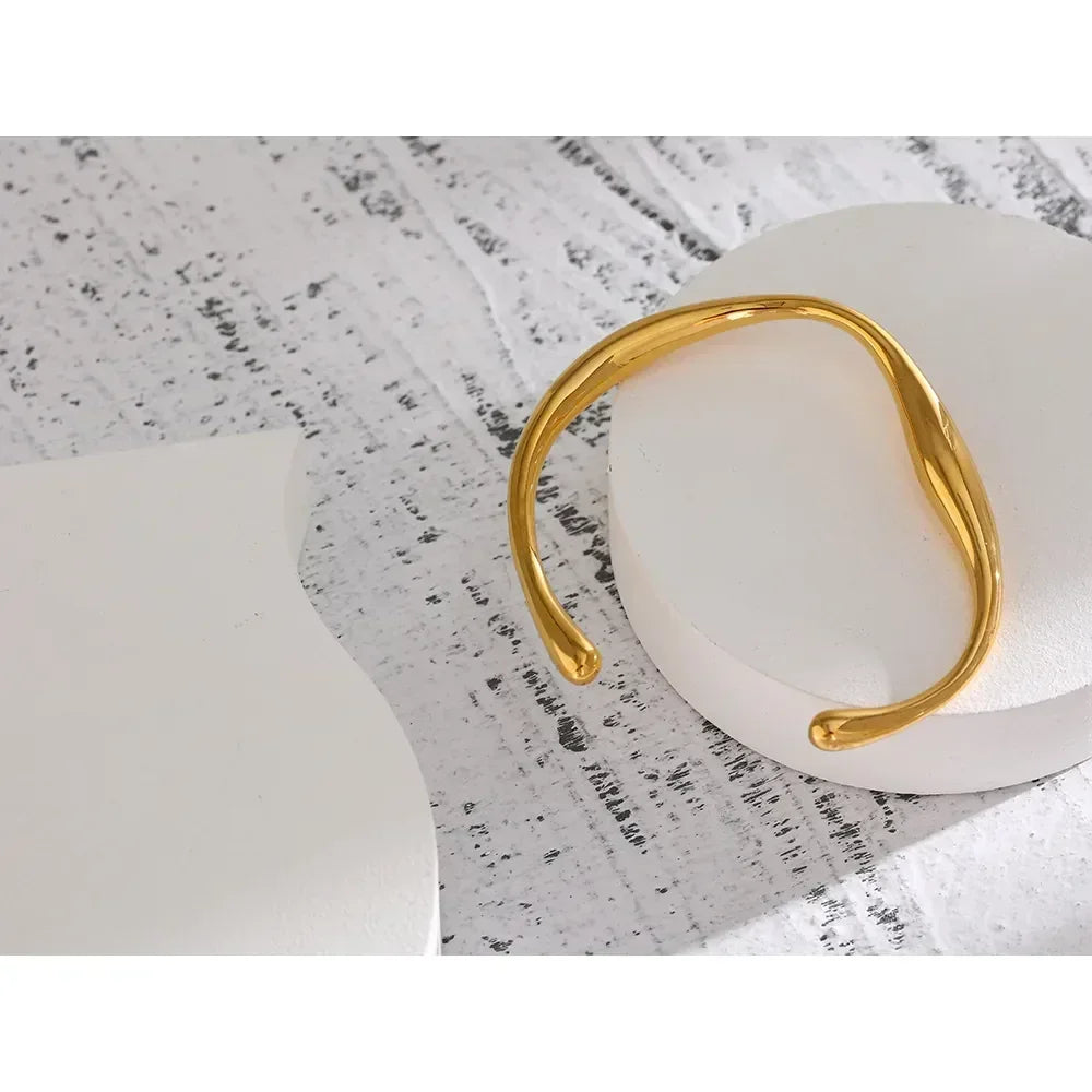 Elegant 18K gold-plated open cuff bracelet on a white textured surface