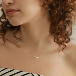 Woman wearing delicate gold-plated necklace with small white pearls, elegant jewelry fashion