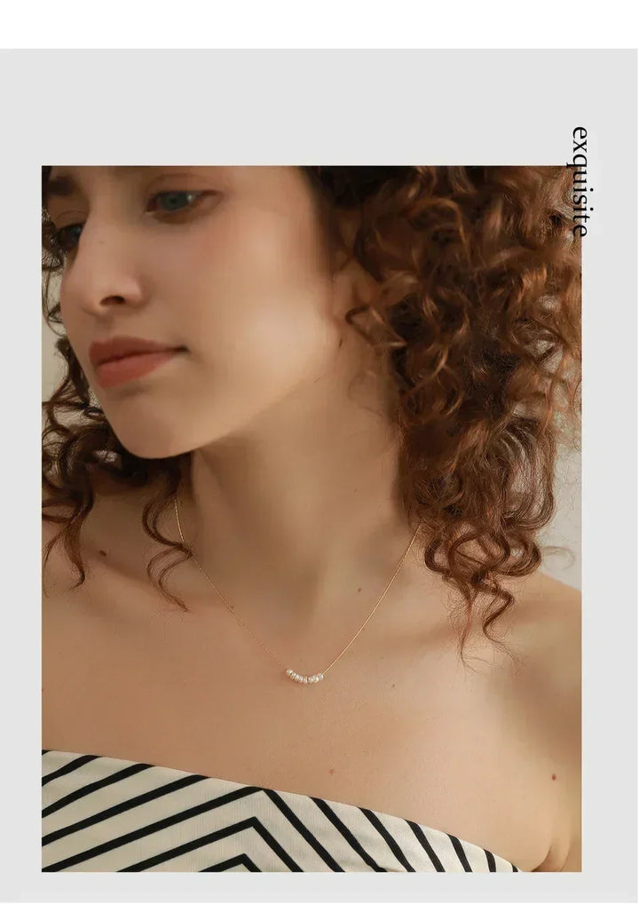 Woman wearing delicate gold-plated necklace with small white pearls, elegant jewelry fashion