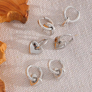 Silver hoop earrings on a textured beige surface with wooden elements.