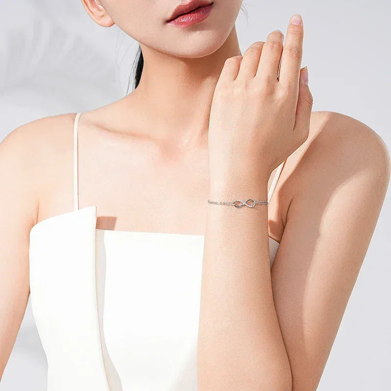 Woman wearing a delicate 925 silver infinity bracelet in a minimalist, elegant setting