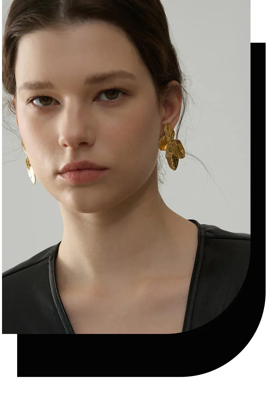 Woman wearing large gold-plated leaf statement earrings and a black top