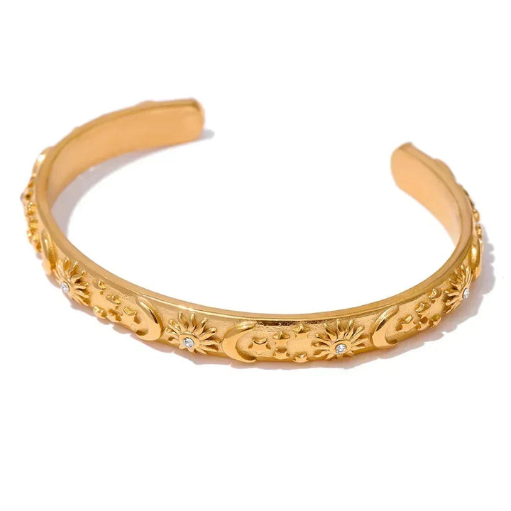 Gold bracelet with intricate designs on a white background