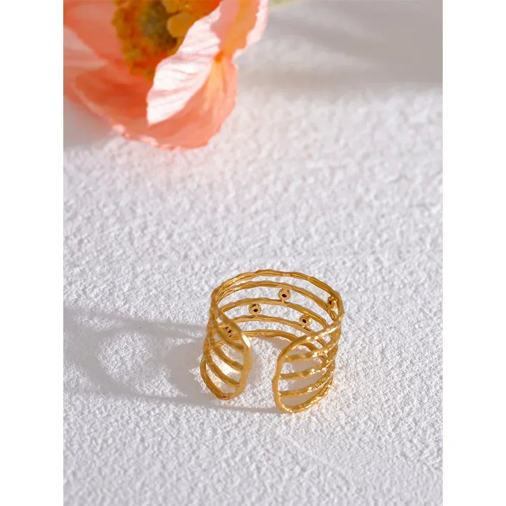 18K gold-plated open band ring with textured, layered design on white textured surface