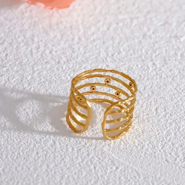 18K gold-plated open band ring with textured, layered design on white textured surface
