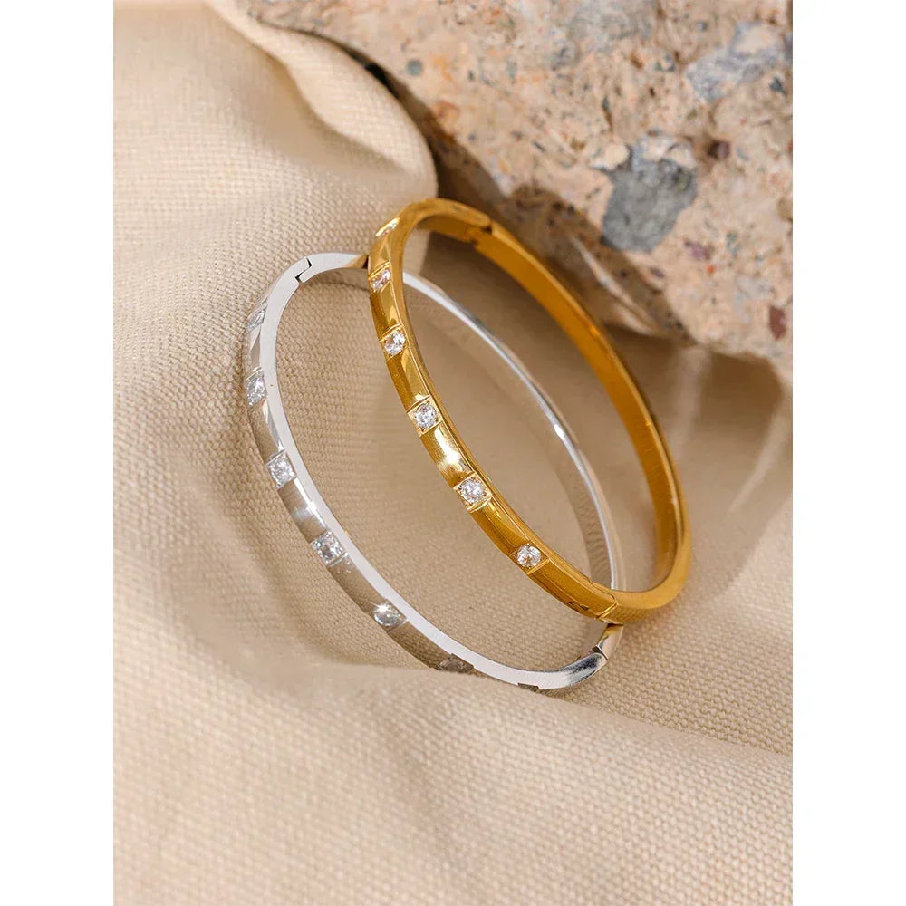 Gold and silver bangle bracelets with cubic zirconia stones on beige fabric