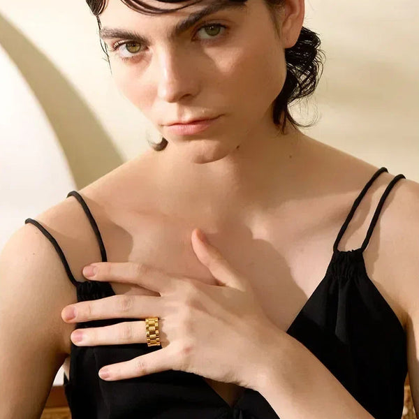 Woman wearing a chunky gold-plated statement ring and black sleeveless top