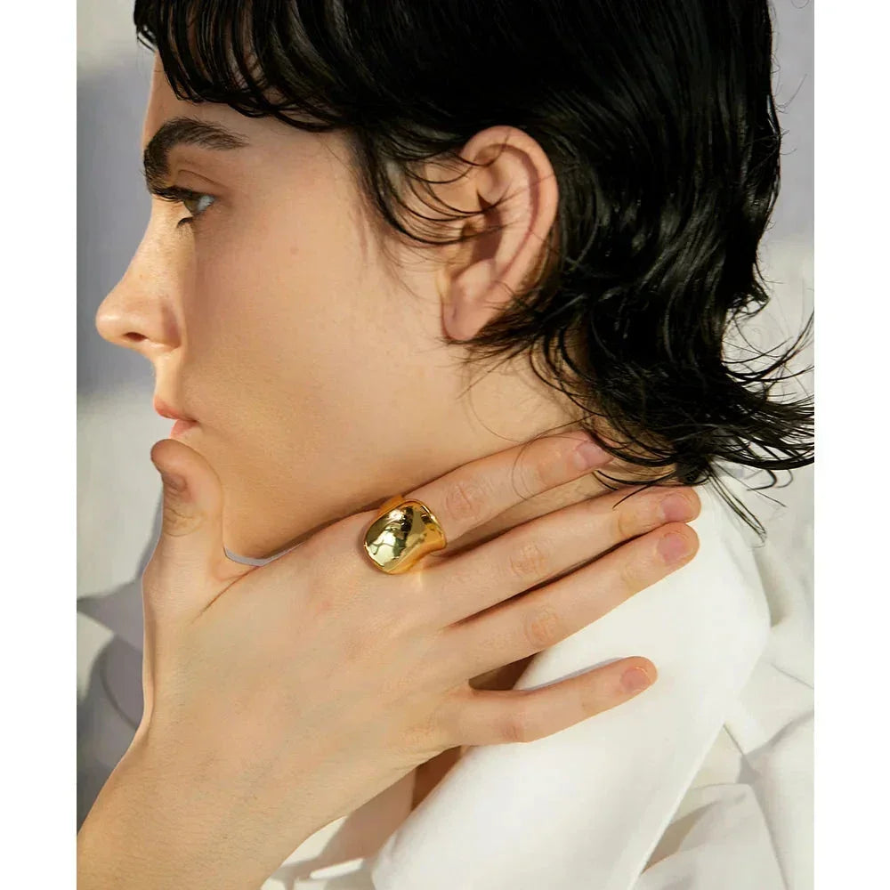 Woman wearing chunky gold-plated statement ring on hand, elegant jewelry close-up