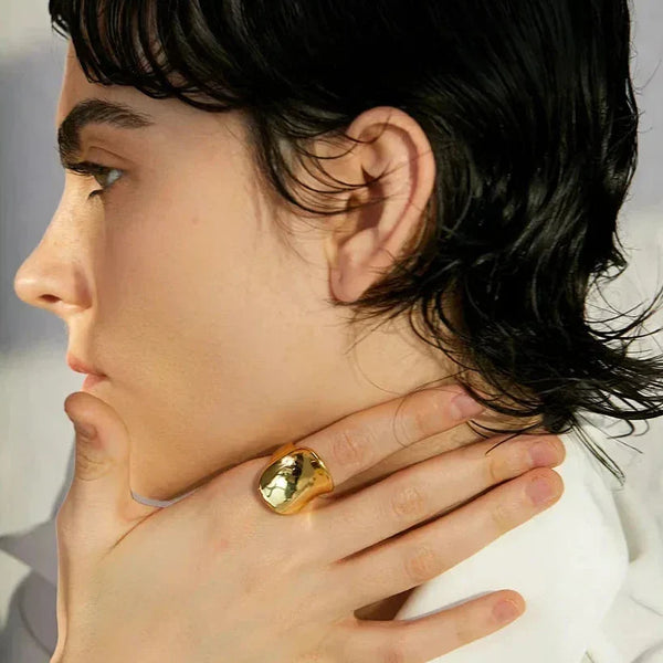 Woman wearing chunky gold-plated statement ring on hand, elegant jewelry close-up