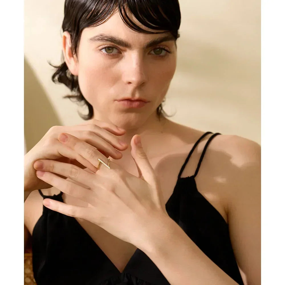 Woman in black dress wearing gold-plated zigzag ring on hand, elegant jewelry close-up