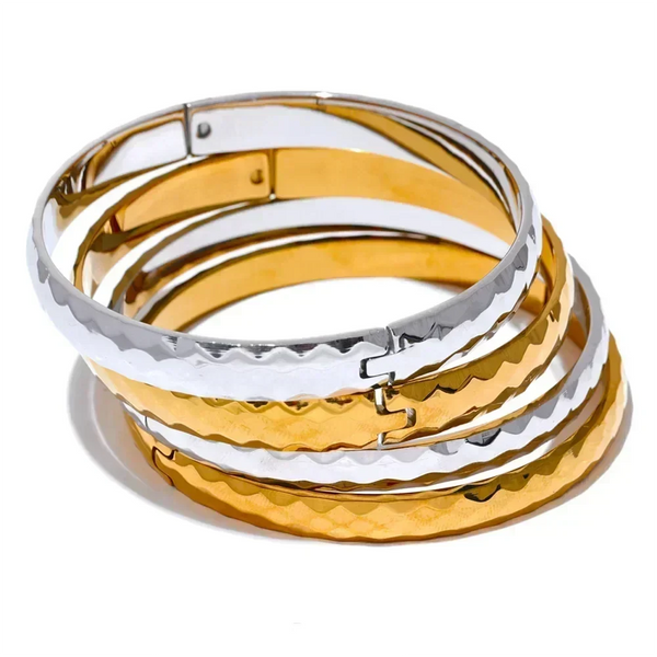 Stacked steel and 18K gold-plated textured bangles on white background