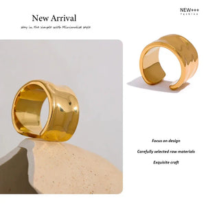 Wide gold-plated ring with hammered texture on a light textured background