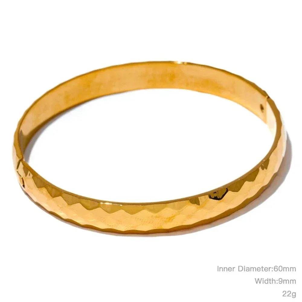 Hammered gold-plated bangle bracelet with a shiny finish on a white background.