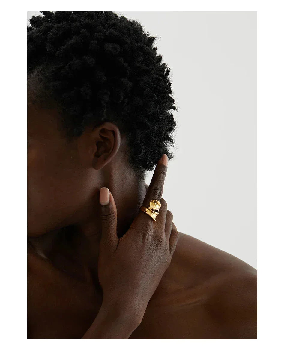 Woman wearing a bold 18K gold-plated statement ring on her finger, minimal background