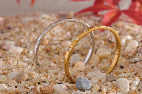 Gold and silver bangle bracelets with cubic zirconia stones on beige fabric