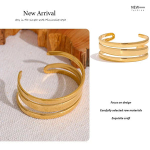 Gold cuff bracelet on a textured surface with 'NEW++' branding.