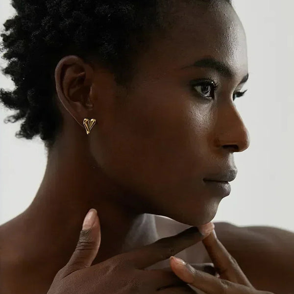 Woman wearing elegant gold-plated heart stud earrings, close-up side profile