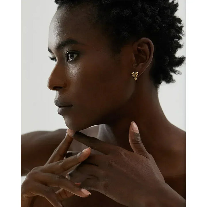 Woman wearing elegant gold-plated heart stud earrings, close-up side profile