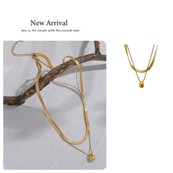Gold necklace with a small pendant on a branch against a light background