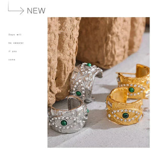 Decorative rings with green gemstones on a textured surface with stone background
